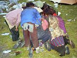 6 5 Children From Yulok Village Crowd Around Book At Kharta Camp The children followed us all the way back to our camp, staying a couple of metres behind us. When we got back to the camp, Kumar brought out a book with photos and they eagerly crowded around turning each page with anticipation. I noticed that the older girl wore an animal hide on her back, connected with small strings to the large metal belt on the front.